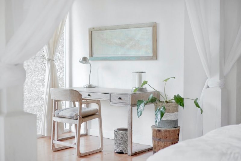 A white bedroom and office space with wooden desk